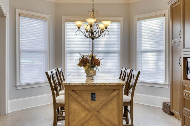 tiled dining room featuring a healthy amount of sunlight, ornamental molding, and a notable chandelier