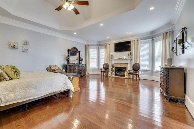 bedroom featuring a tray ceiling, ceiling fan, ornamental molding, and hardwood / wood-style flooring