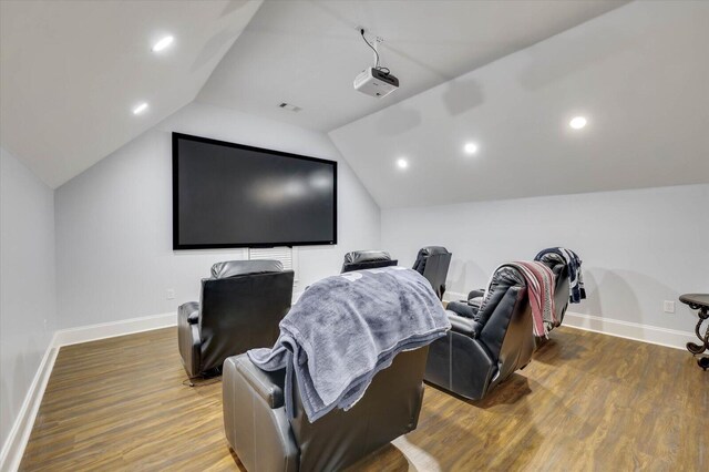 cinema with dark hardwood / wood-style flooring and vaulted ceiling