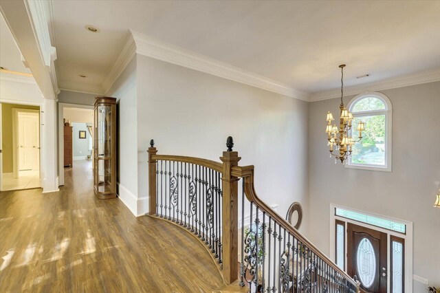 foyer with hardwood / wood-style flooring, a notable chandelier, and crown molding