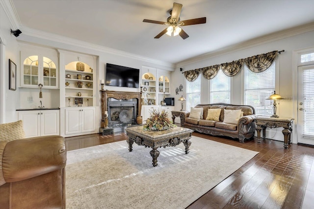 living room with built in shelves, dark hardwood / wood-style flooring, plenty of natural light, and ceiling fan