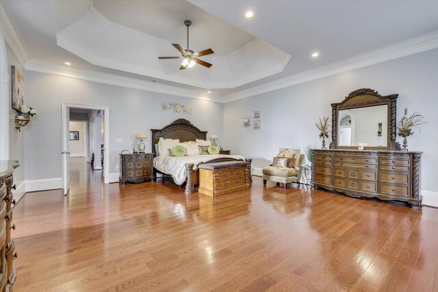 bedroom with a tray ceiling, ceiling fan, light hardwood / wood-style flooring, and ornamental molding