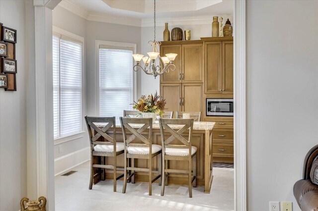 dining space featuring a raised ceiling, ornamental molding, and an inviting chandelier