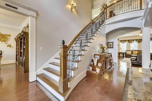 staircase featuring hardwood / wood-style flooring, ceiling fan, and crown molding