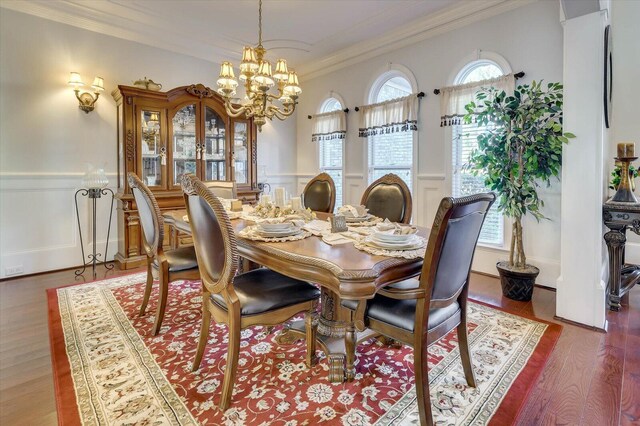 dining space with hardwood / wood-style floors, an inviting chandelier, and crown molding