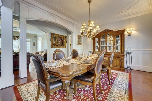 dining space featuring ornamental molding, dark wood-type flooring, and a notable chandelier