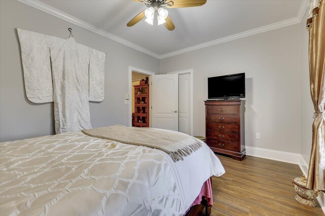 bedroom with dark wood-type flooring, a closet, ceiling fan, and ornamental molding