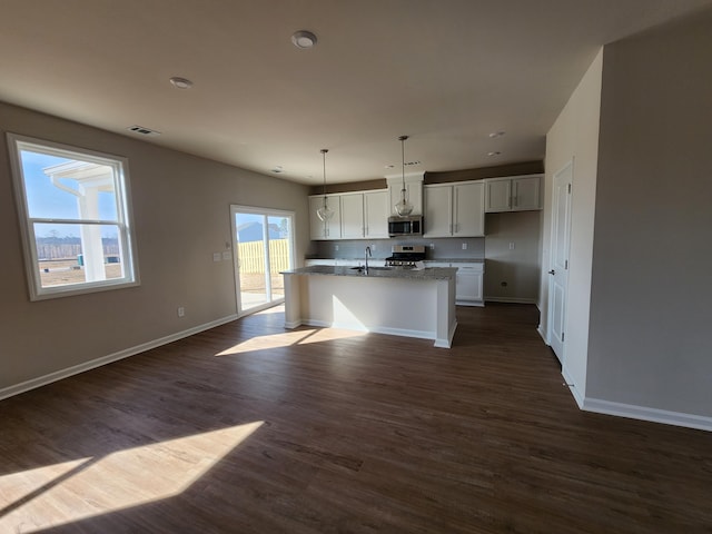 kitchen with pendant lighting, sink, a kitchen island with sink, stainless steel appliances, and white cabinets