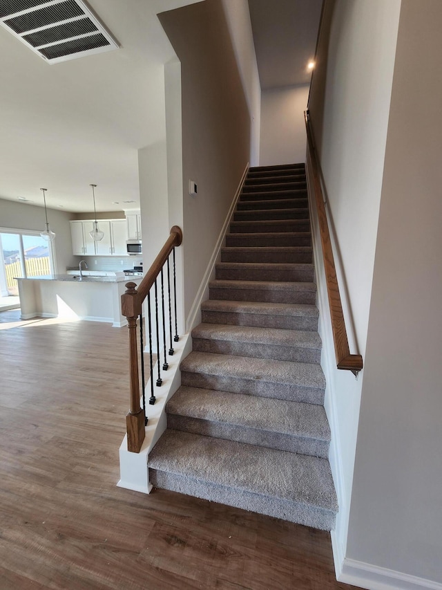 staircase featuring wood-type flooring and sink