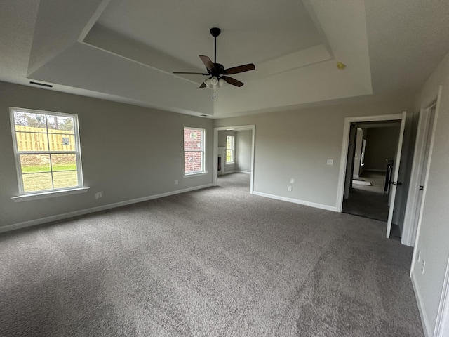 carpeted spare room with a tray ceiling and ceiling fan