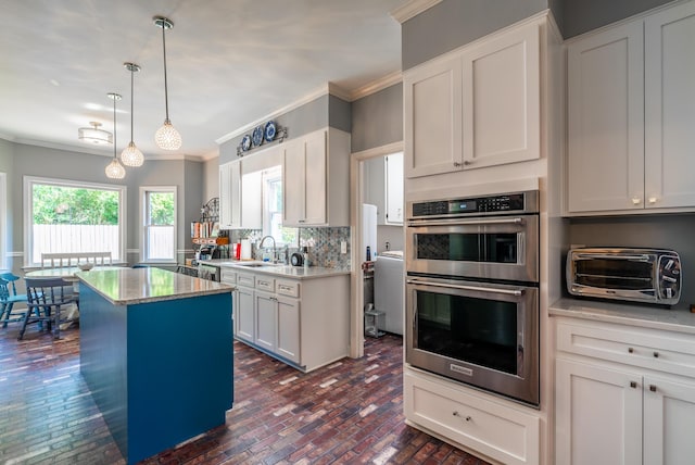 kitchen with white cabinetry, double oven, a center island, and hanging light fixtures