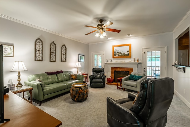 carpeted living room featuring a brick fireplace, crown molding, and ceiling fan