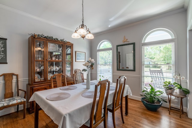 dining room featuring wood-type flooring, crown molding, and a chandelier