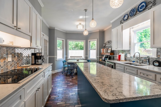 kitchen featuring backsplash, black electric cooktop, a center island, hanging light fixtures, and sink