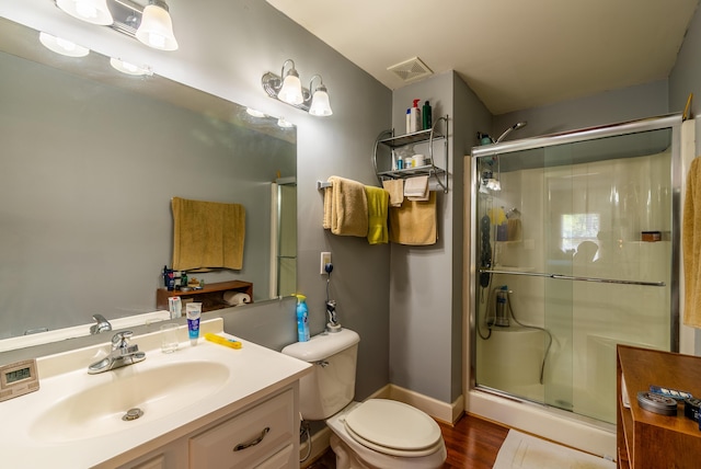 bathroom with toilet, a shower with shower door, hardwood / wood-style flooring, and vanity