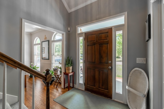 foyer featuring light wood-type flooring, ornamental molding, and lofted ceiling