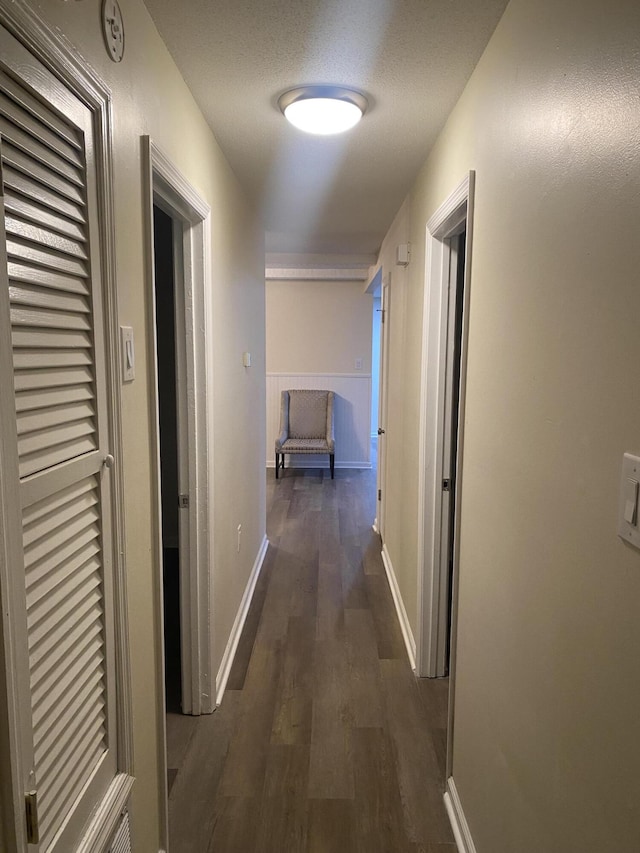 hall with a textured ceiling and dark wood-type flooring