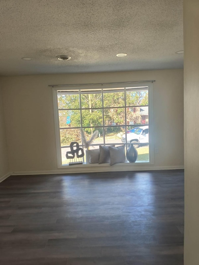 empty room with dark hardwood / wood-style flooring and a textured ceiling