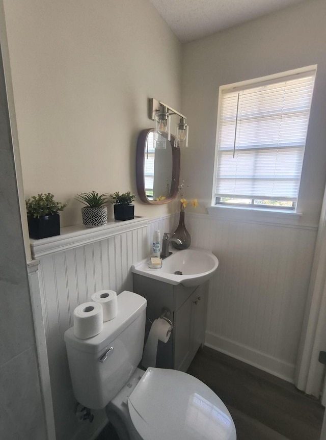 bathroom with toilet, vanity, a textured ceiling, and hardwood / wood-style flooring