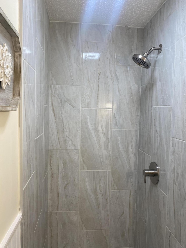 bathroom featuring tiled shower and a textured ceiling