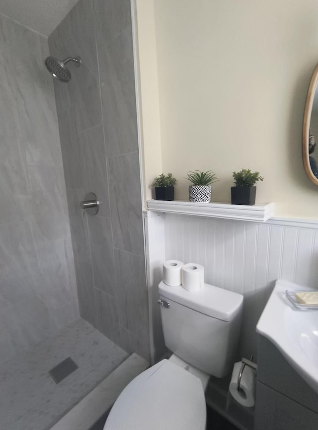 bathroom with toilet, vanity, and tiled shower