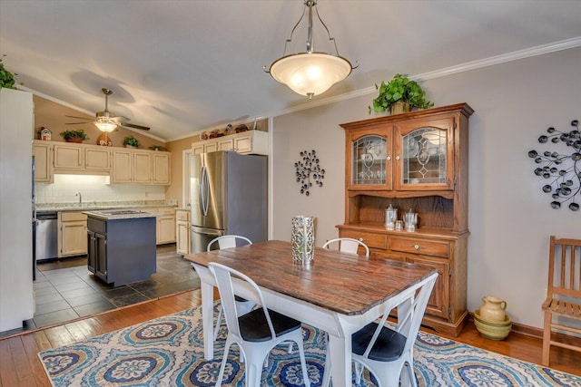 dining area featuring ceiling fan, dark hardwood / wood-style flooring, vaulted ceiling, crown molding, and sink