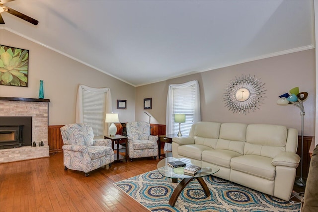 living room featuring lofted ceiling, a fireplace, crown molding, and hardwood / wood-style flooring