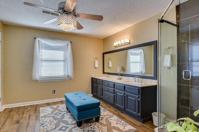 bathroom with wood-type flooring, vanity, a wealth of natural light, and a textured ceiling