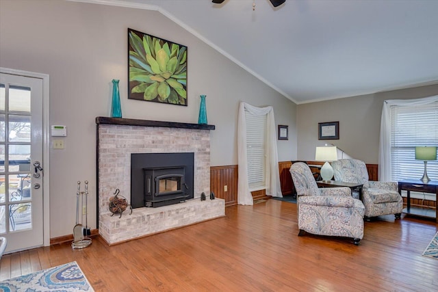 living room featuring wood-type flooring, ornamental molding, and vaulted ceiling