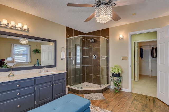 bathroom with a shower with door, a textured ceiling, vanity, and ceiling fan