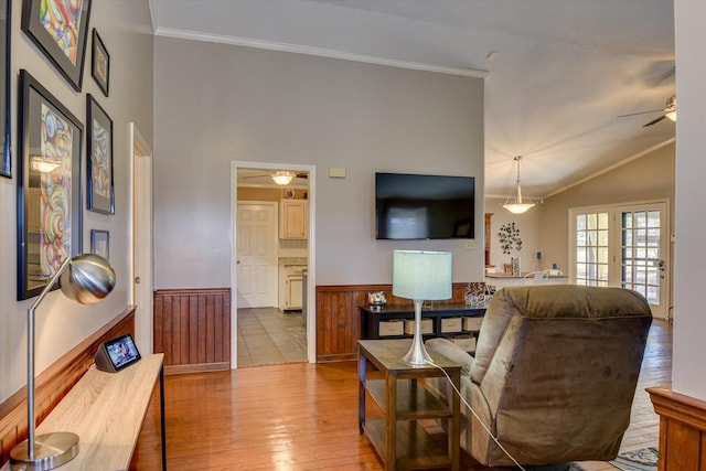 living room featuring ceiling fan, light hardwood / wood-style flooring, ornamental molding, and vaulted ceiling