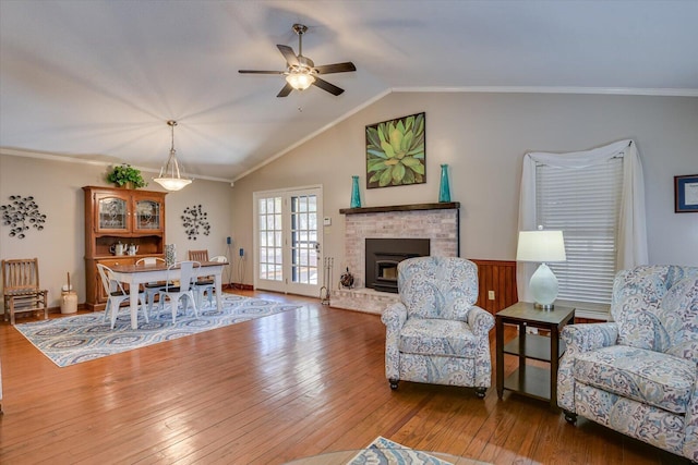 living room with lofted ceiling, wood-type flooring, a fireplace, ornamental molding, and ceiling fan