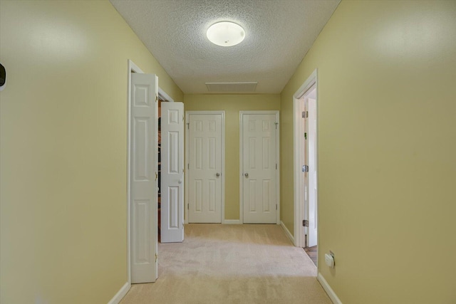 hall with light carpet and a textured ceiling