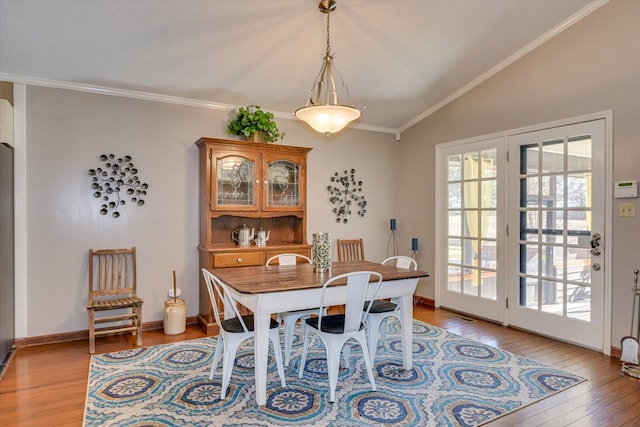 dining area featuring light wood-type flooring, a healthy amount of sunlight, vaulted ceiling, and crown molding