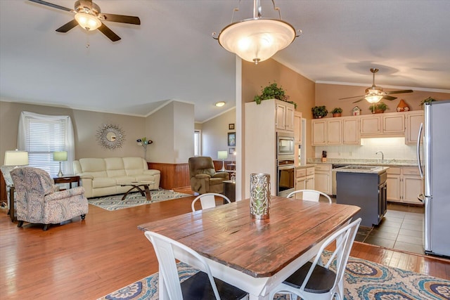 dining room featuring wood-type flooring, crown molding, and vaulted ceiling