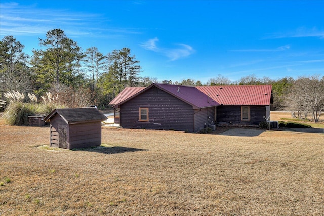 back of property featuring a lawn and a storage shed