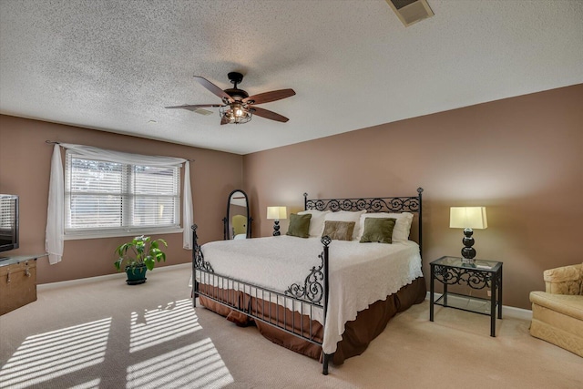 carpeted bedroom with ceiling fan and a textured ceiling