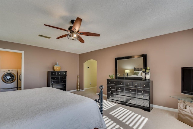 carpeted bedroom with a textured ceiling, separate washer and dryer, and ceiling fan