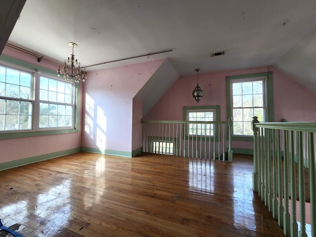 bonus room with lofted ceiling, hardwood / wood-style flooring, and a chandelier