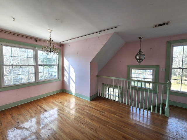 bonus room featuring wood-type flooring and a notable chandelier