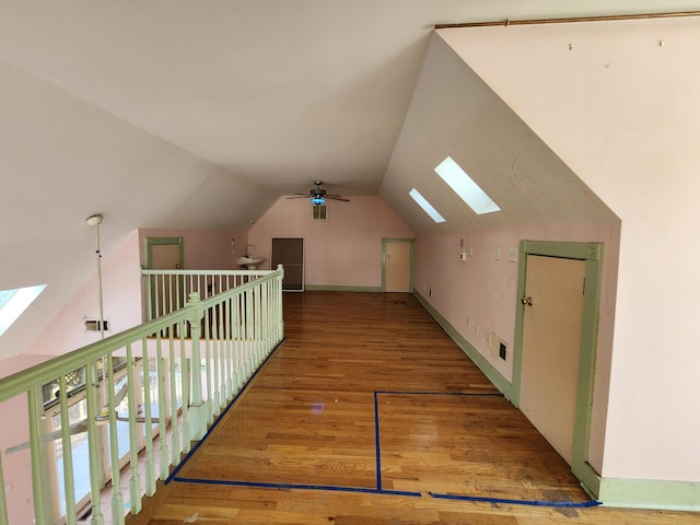 additional living space featuring vaulted ceiling with skylight, hardwood / wood-style floors, and ceiling fan