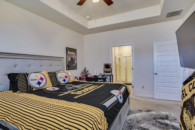 carpeted bedroom featuring a raised ceiling, ceiling fan, and ensuite bathroom