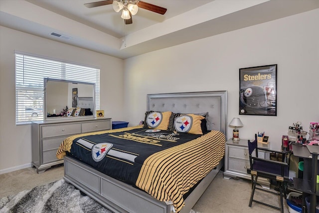 bedroom featuring multiple windows, a tray ceiling, ceiling fan, and light colored carpet