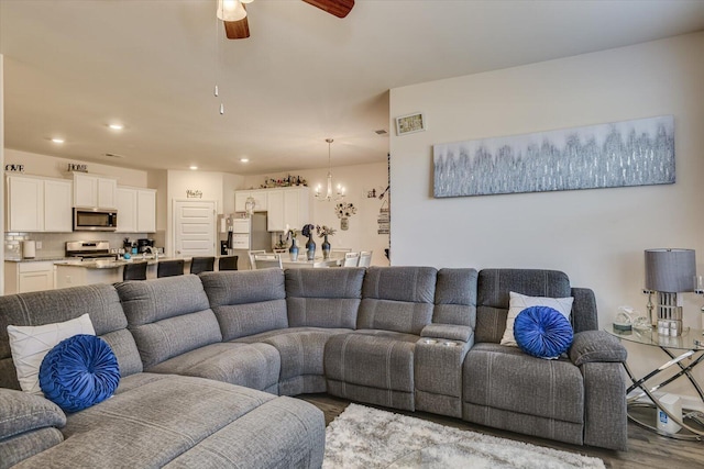 living room with hardwood / wood-style flooring and ceiling fan with notable chandelier