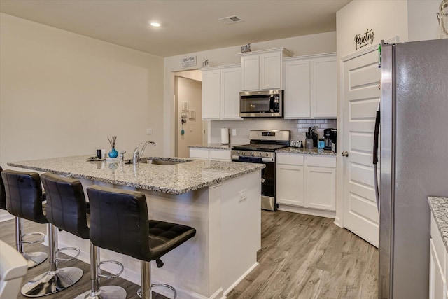 kitchen with a kitchen bar, sink, white cabinets, and appliances with stainless steel finishes