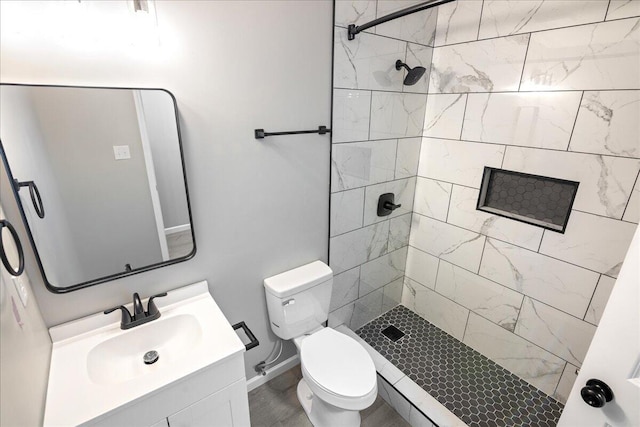 bathroom featuring vanity, tiled shower, and toilet