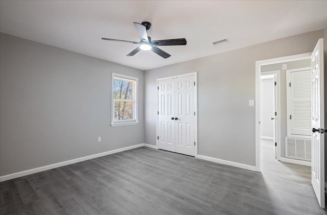 unfurnished bedroom with dark hardwood / wood-style floors, a closet, and ceiling fan