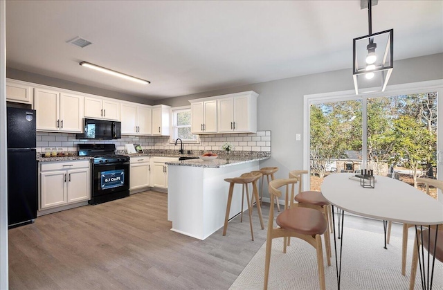 kitchen with white cabinetry, pendant lighting, kitchen peninsula, and black appliances