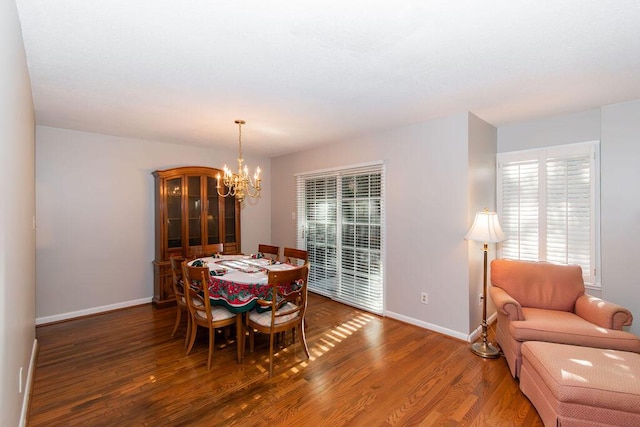 dining area with dark hardwood / wood-style flooring and an inviting chandelier