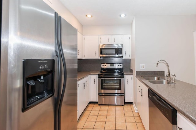 kitchen with appliances with stainless steel finishes, backsplash, sink, light tile patterned floors, and white cabinets